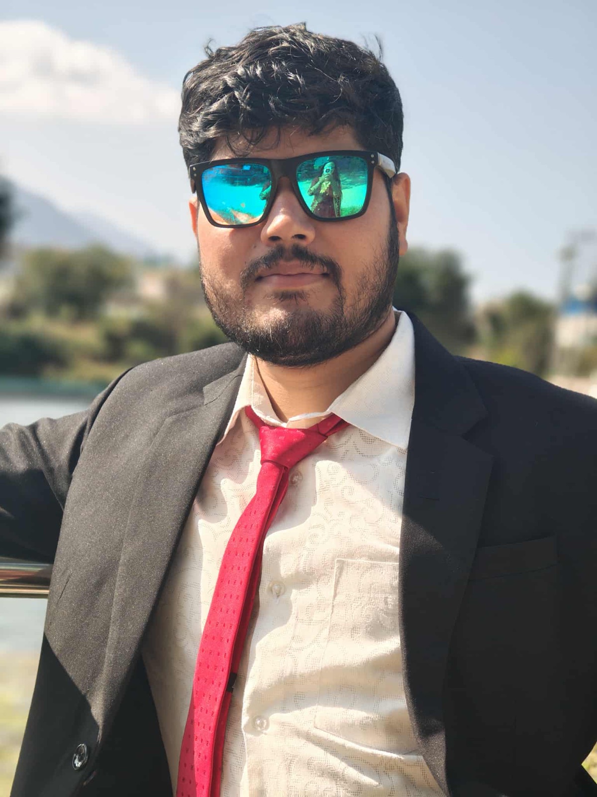 Pramesh Basnet, zoologist and environmental enthusiast, in a dark suit and red tie outdoors in Nepal